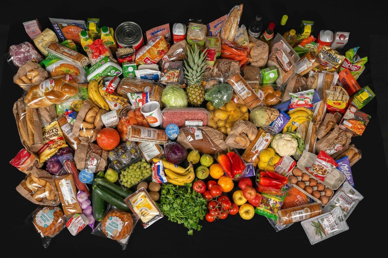 Lebensmittelvielfalt mit Obst, Gemüse, Brot, Eiern und Fleisch vor schwarzem Hintergrund